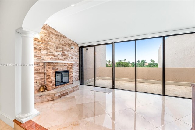 unfurnished living room with lofted ceiling, expansive windows, and a stone fireplace