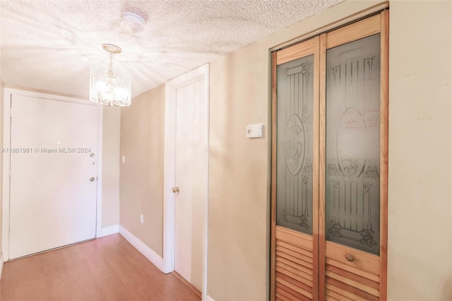 hall featuring a textured ceiling, a chandelier, and wood-type flooring