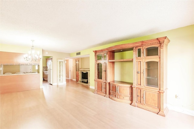 unfurnished living room with a notable chandelier, a textured ceiling, and hardwood / wood-style flooring