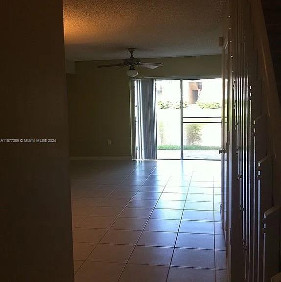 tiled empty room featuring a textured ceiling and ceiling fan