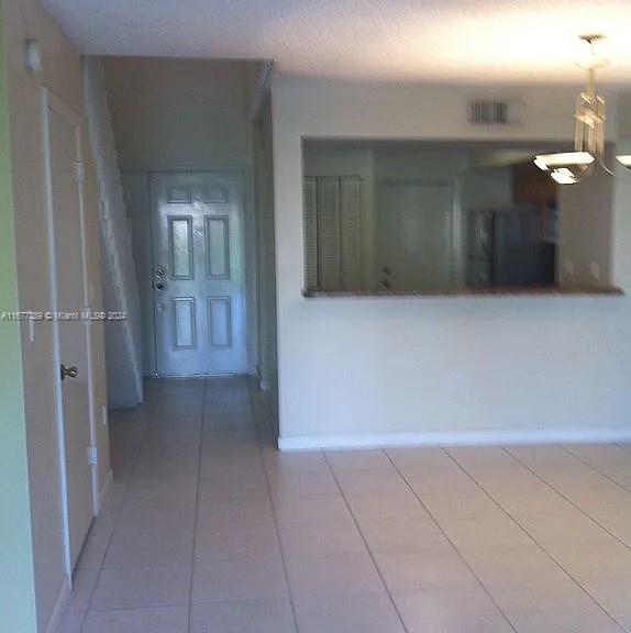 hallway with a textured ceiling and tile patterned flooring