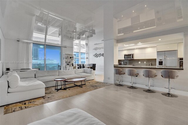 living room featuring light wood-type flooring, a towering ceiling, and sink