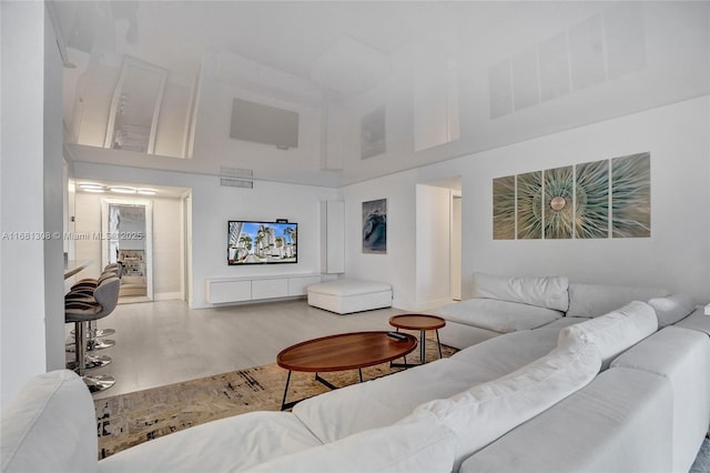 living room featuring visible vents, wood finished floors, and a towering ceiling