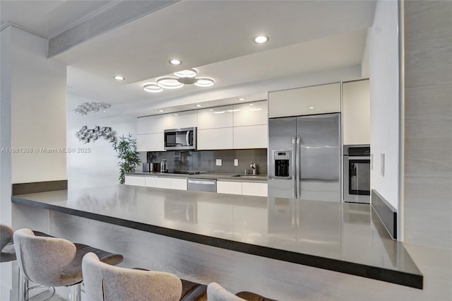 kitchen with a kitchen breakfast bar, kitchen peninsula, stainless steel appliances, and white cabinets