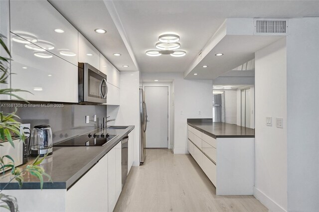 kitchen with sink, white cabinetry, light hardwood / wood-style flooring, and stainless steel appliances