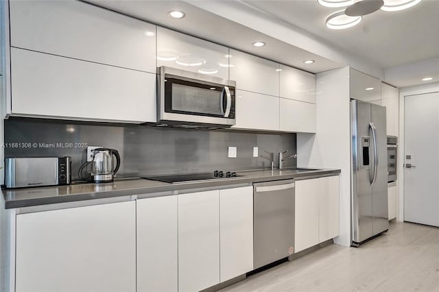 kitchen with dark countertops, modern cabinets, white cabinetry, and stainless steel appliances