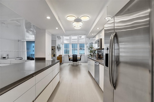 kitchen featuring floor to ceiling windows, stainless steel appliances, a tray ceiling, white cabinets, and light hardwood / wood-style flooring