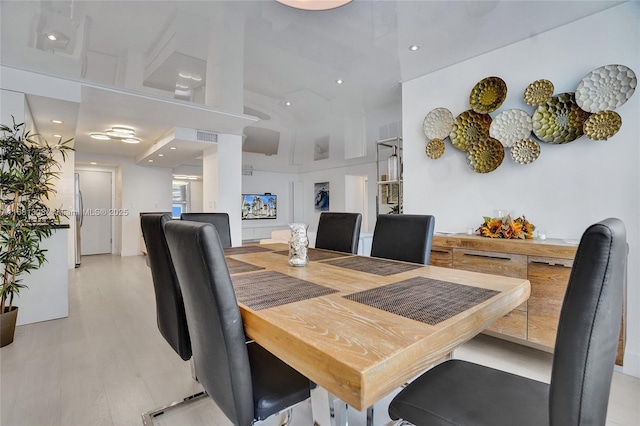 dining area with light wood-style flooring and a high ceiling