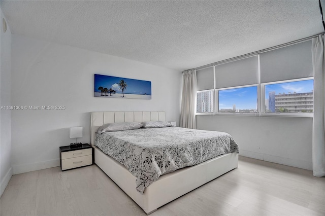 bedroom featuring a textured ceiling and light hardwood / wood-style floors