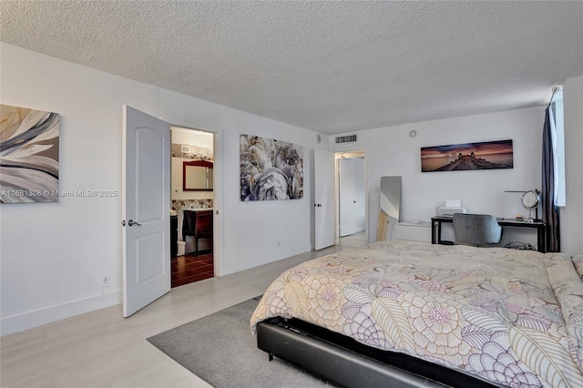 bedroom featuring a textured ceiling and ensuite bath