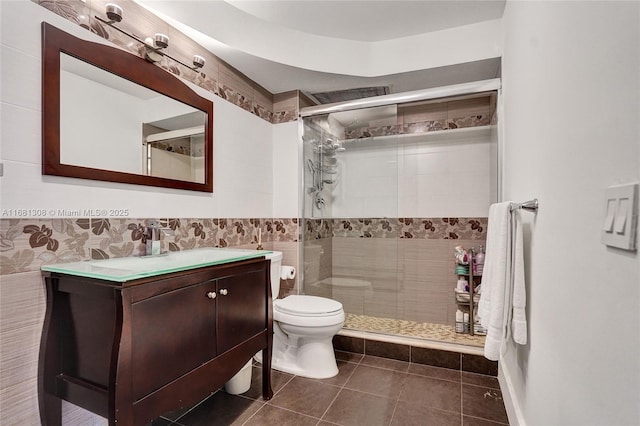 full bathroom with tile patterned flooring, toilet, vanity, tile walls, and a shower stall