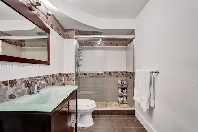 bathroom featuring toilet, tile patterned flooring, tile walls, an enclosed shower, and vanity