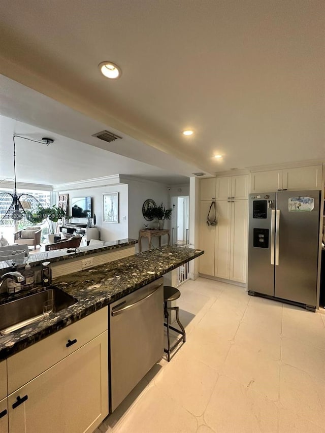 kitchen featuring dark stone countertops, sink, white cabinets, pendant lighting, and appliances with stainless steel finishes