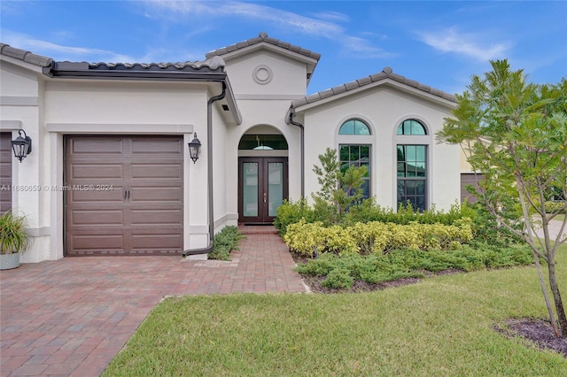 mediterranean / spanish house featuring a garage, french doors, and a front lawn