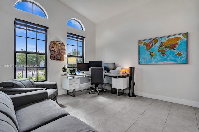 home office featuring high vaulted ceiling, light tile patterned flooring, and baseboards