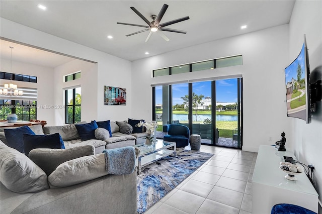 living room featuring a high ceiling, light tile patterned floors, and ceiling fan with notable chandelier