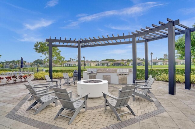 view of patio with area for grilling, a grill, a pergola, and a fire pit