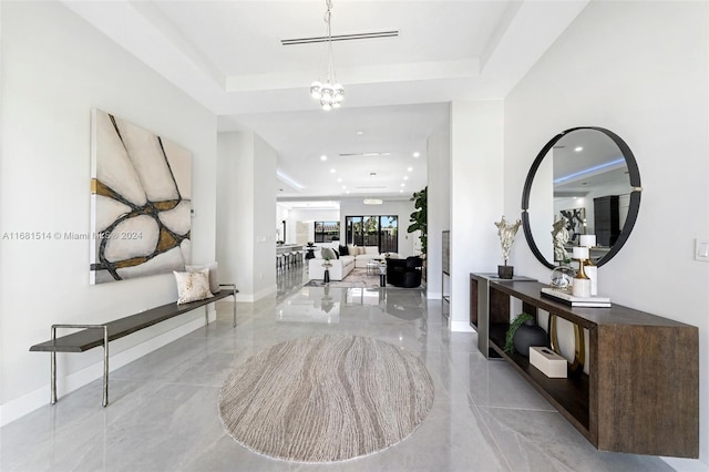 foyer entrance featuring a tray ceiling and an inviting chandelier