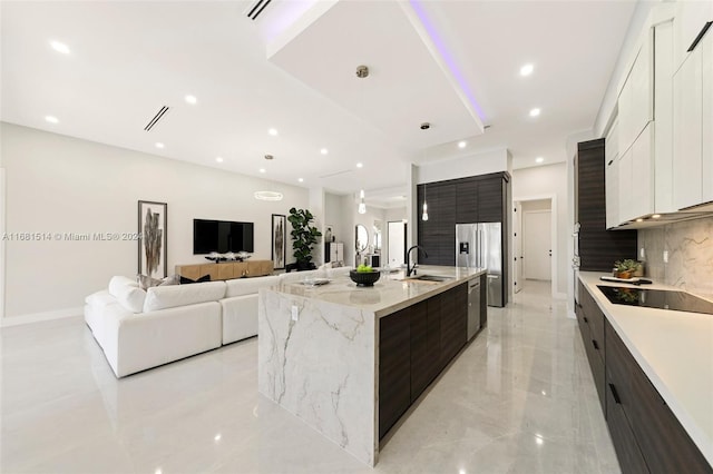 kitchen with tasteful backsplash, sink, white cabinetry, a large island, and stainless steel appliances