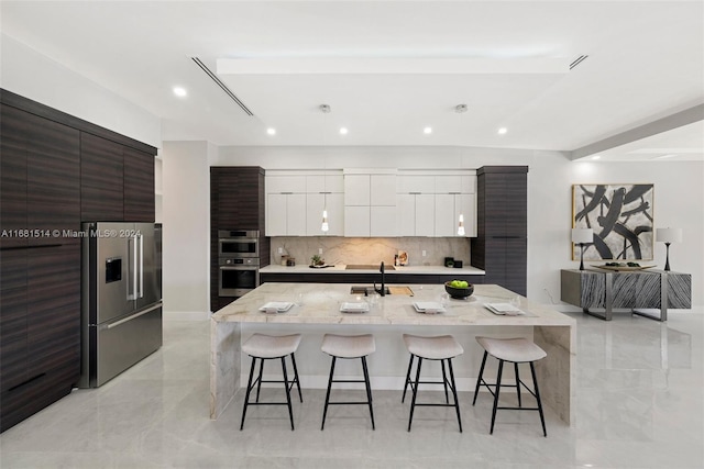 kitchen with decorative backsplash, a breakfast bar, white cabinets, and stainless steel appliances