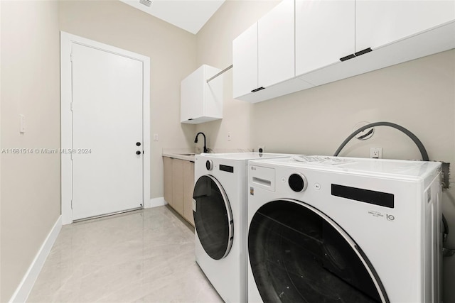 washroom featuring sink, washing machine and dryer, and cabinets