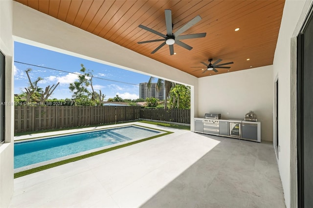 view of swimming pool featuring exterior kitchen, area for grilling, a patio, and ceiling fan