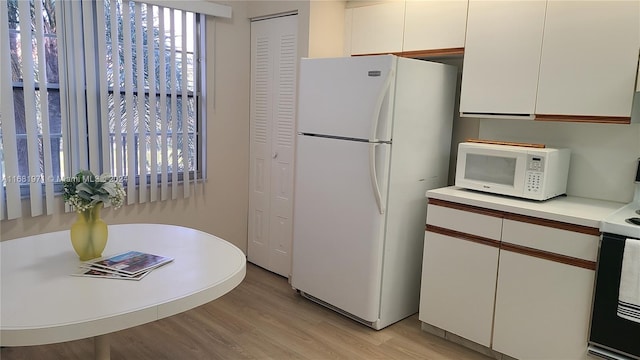 kitchen with white cabinets, white appliances, and light hardwood / wood-style flooring