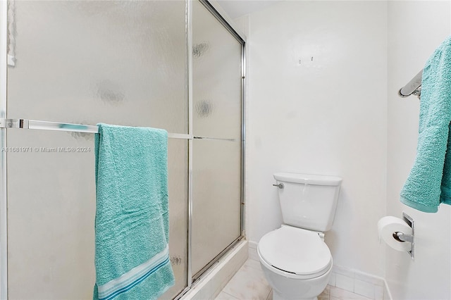 bathroom with an enclosed shower, toilet, and tile patterned floors