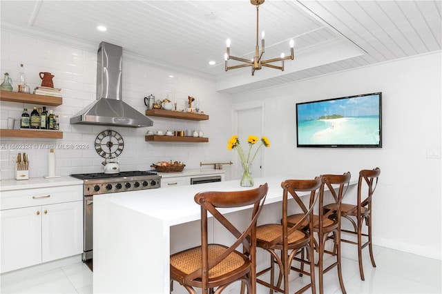 kitchen featuring white cabinets, tasteful backsplash, a kitchen breakfast bar, high end stainless steel range, and wall chimney exhaust hood