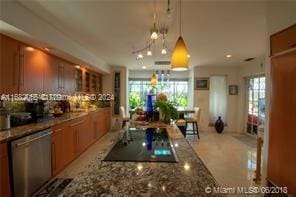 kitchen featuring plenty of natural light, pendant lighting, dark stone countertops, and stainless steel dishwasher