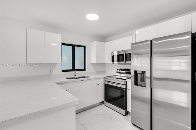 kitchen featuring white cabinetry, light stone countertops, stainless steel appliances, and sink