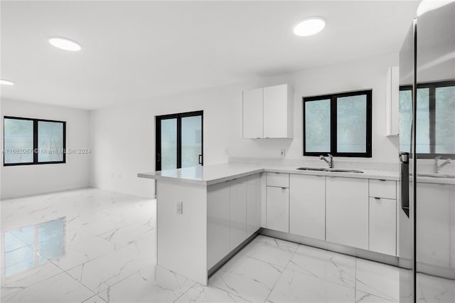 kitchen with kitchen peninsula, white cabinetry, and sink