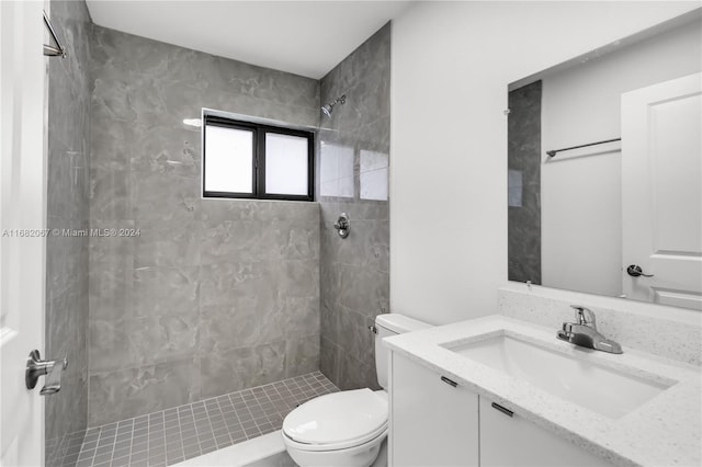 bathroom featuring vanity, toilet, and tiled shower