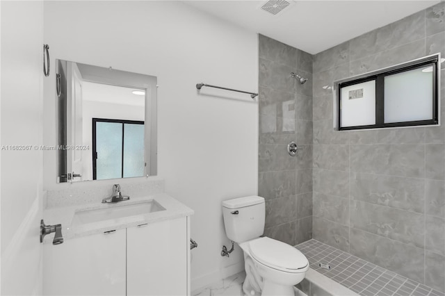 bathroom with vanity, toilet, and a tile shower