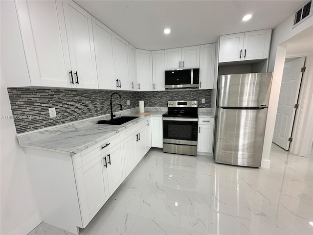 kitchen featuring backsplash, white cabinetry, light stone countertops, sink, and stainless steel appliances