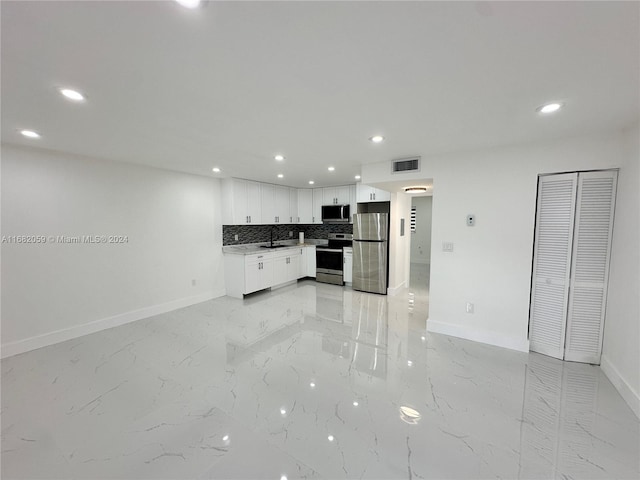 kitchen featuring appliances with stainless steel finishes, white cabinetry, tasteful backsplash, and sink