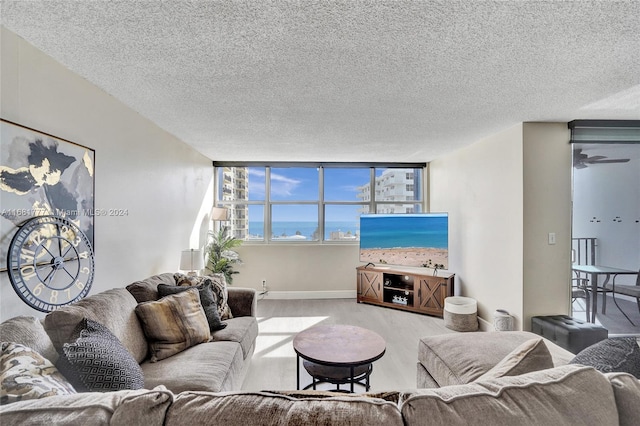 living room featuring a textured ceiling, light hardwood / wood-style flooring, and a wall of windows