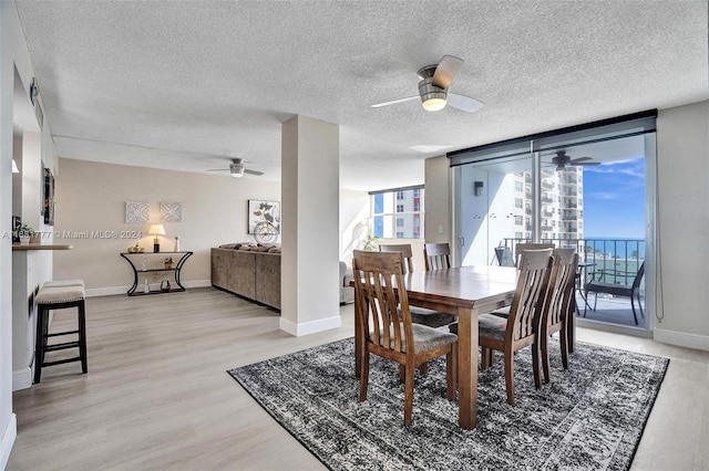 dining room with ceiling fan, light hardwood / wood-style flooring, expansive windows, and a textured ceiling