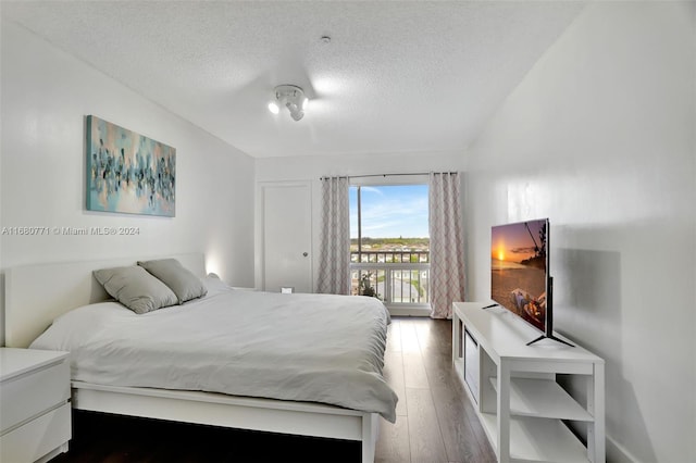 bedroom with dark wood-type flooring, access to exterior, and a textured ceiling