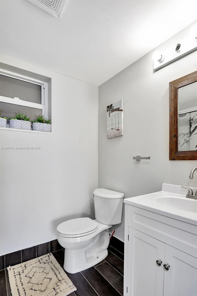 bathroom with toilet, hardwood / wood-style floors, and vanity