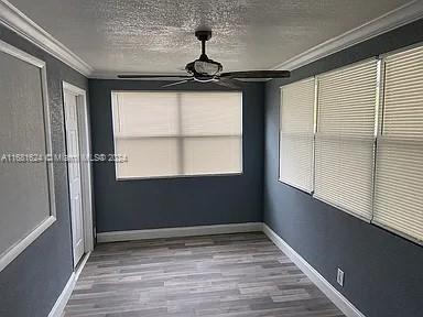 unfurnished room with crown molding, hardwood / wood-style flooring, and a textured ceiling