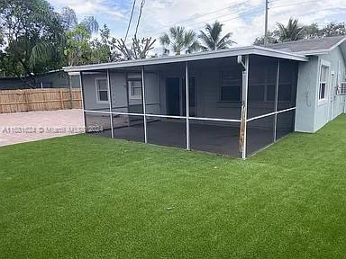 rear view of house with a yard, a sunroom, and a patio area