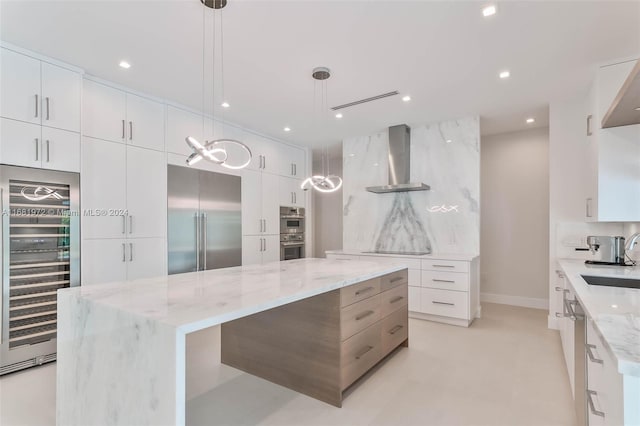 kitchen with stainless steel appliances, wall chimney range hood, beverage cooler, and hanging light fixtures