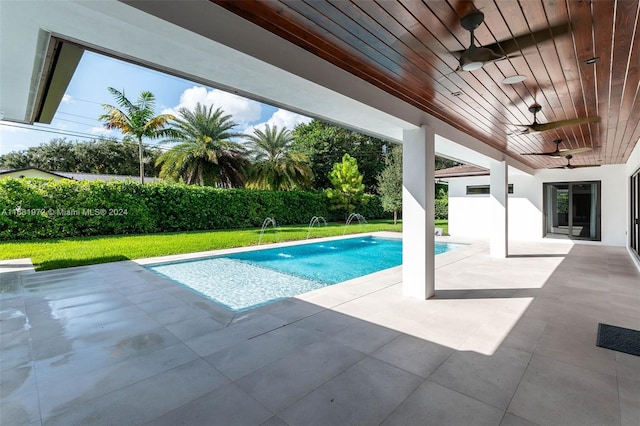 view of pool with a yard, ceiling fan, pool water feature, and a patio area