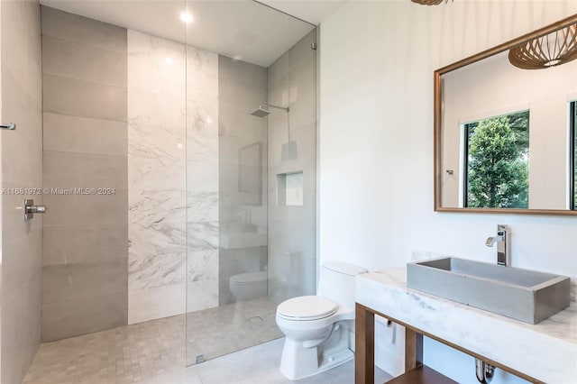 bathroom featuring toilet, vanity, and tiled shower