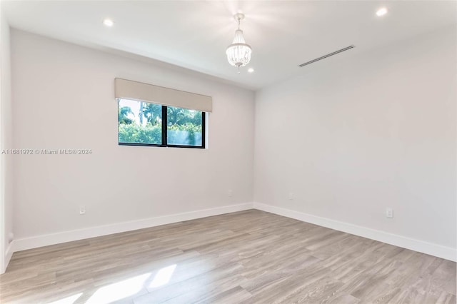 empty room featuring a chandelier and light wood-type flooring