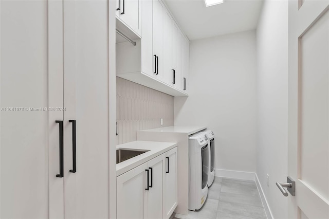 laundry area featuring sink, washing machine and clothes dryer, and cabinets