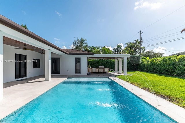 view of pool with a patio, ceiling fan, pool water feature, and a lawn