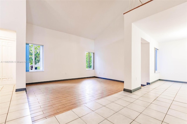 unfurnished room with plenty of natural light, high vaulted ceiling, and light wood-type flooring