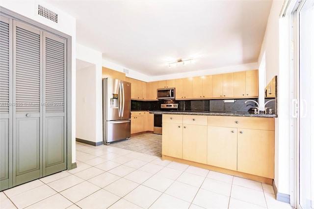 kitchen featuring dark stone counters, kitchen peninsula, backsplash, and stainless steel appliances